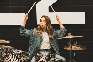 Creativity and music. Young beautiful girl plays the drums. Recording Studio. Musical equipment.