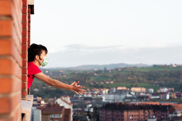 young girl remains at home during the world crisis caused by the coronavirus. She leans out the window and raises her arms in despair. quarantine and health concept. stay at home