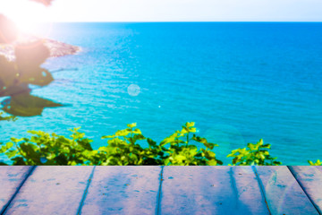 Blue wooden plank against to sea and green plants. Blank flat wooden table.