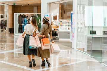 Shopping and entertainment, mall inside. Two beautiful girls with paper bags at the mall. The joy of consumption, Gift shopping, holiday.
