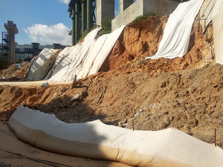 The geotextile fabric is spread over the surface of the slope to prevent erosion. Also to...