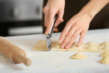 Woman preparing tasty ravioli on table