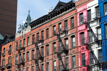 Fototapeta premium Row of Old Colorful Brick Residential Buildings in Hell's Kitchen of New York City with Fire Escapes