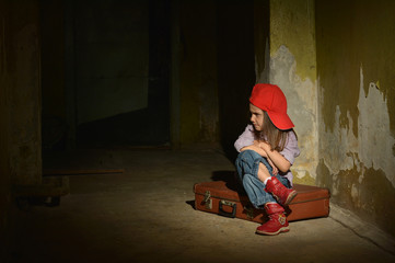 Lonely little girl in a dark cellar