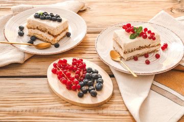 Tasty tiramisu with berries on wooden background