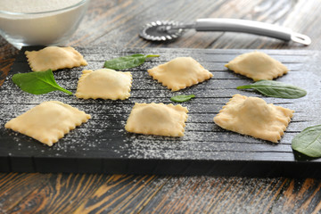 Raw ravioli on wooden board