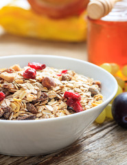 Breakfas bowl with muesli, fruits and nuts on a table, close up view