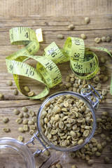 Green coffee beans and yellow measure tape on wood table