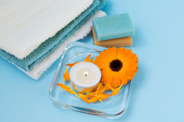 Beautiful spa composition. Candle, soft cotton towels, soap and calendula officinalis flower. The concept of health and alternative medicine. View from above.