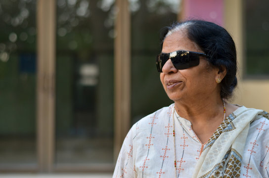 Portrait Of A Happy Retired Indian Woman Wearing UV-protecting Sunglasses For Physical Protection Of Eye Immediately After Surgery. Showing A Victory Sign - Defeat Cataract 