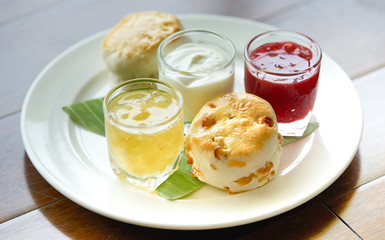 scone with pineapple jam and strawberry jam and cream in plate