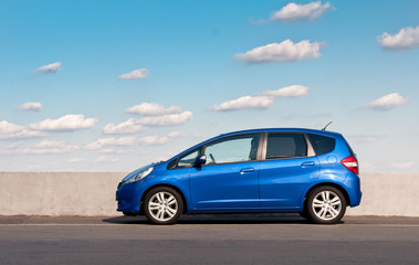 Blue car parked on the road against the background of the sunny sky. Automotive photography. Space...