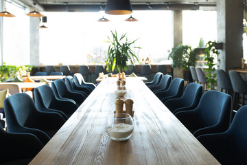 Long wooden table with soft chairs in cozy cafe