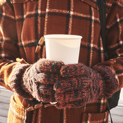 Cardboard glass in hands with gloves and warm clothes in winter