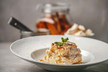 Delicious vegan dietetic desert meringue roll with the sprig of mint in the top in a white modern plate on the gray background 