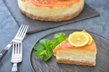 Plate with piece of tasty cheesecake on dark background