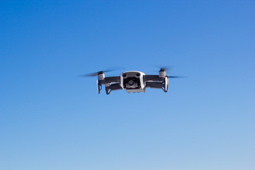 Quadcopter in flight at blue sky background