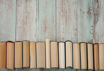Time for yourself, the pleasure of reading. Horizontal row of books close-up on a light wooden background. Free space.