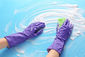Hands of woman cleaning color surface