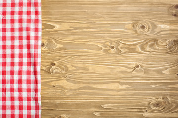 Red checkered tablecloth on wooden table. Background with copy space. Horizontal. Top view.