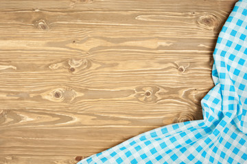 Blue checkered tablecloth on wooden table. Background with copy space. Horizontal. Top view.