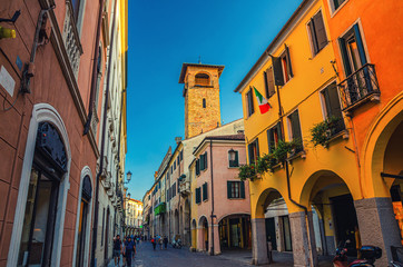 Fototapeta na wymiar Street with old colorful buildings with italian flag on wall and tower in medieval historical city centre of Padua, evening twilight view, Padova town, Veneto Region, Italy