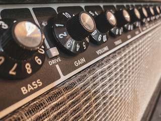 Close up of the black gain knob a vintage electric guitar clean amplifier .music store and business. wallpaper or background with warm vintage filter style. master volume knob. - obrazy, fototapety, plakaty