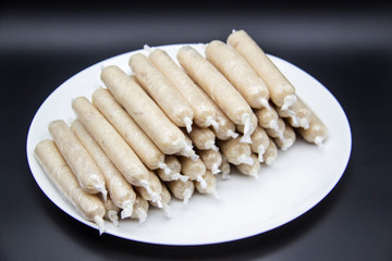 Fragrant fresh sausages made from chicken meat at home non-GMO on the plate. Ukrainian tasty food.  Raw handmade sausages on the plate. Many chicken sausages on the plate against dark background