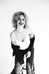 Naklejka premium loki afro, blondynka, emocje, moda, czerwona szminka, dżinsy, biała bluzka, czarna kurtka, czarne rajstopy
