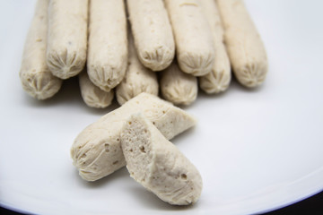 Fragrant fresh sausages made from chicken meat at home non-GMO on the plate. Ukrainian tasty food. Boiled handmade sausages on the plate. Many chicken sausages on the plate against background