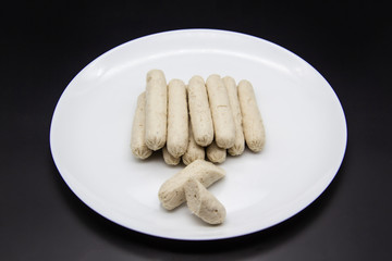 Fragrant fresh sausages made from chicken meat at home non-GMO on the plate. Ukrainian tasty food. Boiled handmade sausages on the plate. Many chicken sausages on the plate against background