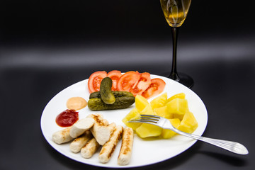 Delicious homemade chicken sausages with tomatoes, cucumbers, potato and souces. Fragrant sausages made from non-GMO chicken. Toasted Mini Sausages from chicken on the plate. Ukrainian tasty food.