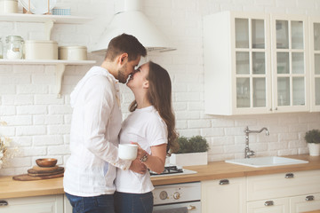 Lifestyle consept at home with couple young men and woman  with cup of coffee or tea in kitchen