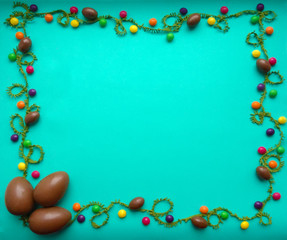 Chocolate eggs and multi-colored candy on a green background