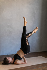 Young woman standing in a yoga exercise position. Girl balancing in a pose on the shoulder blades, practice stretch exercise at yoga class.