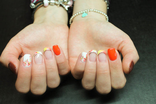 Bright manicure with orange French brown gel Polish and a hand drawn pattern on the hands of a fashionable modern girl