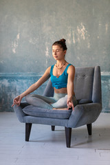 Young women meditating with mudra sign at yoga class or her home. Girl practice sitting on armchair...