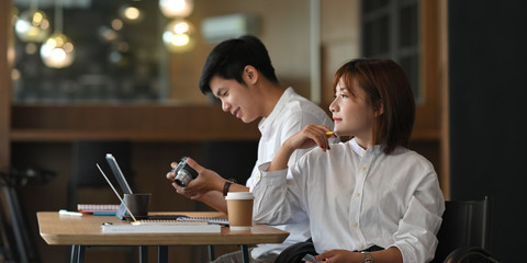 Photo of website administrator team working with computer tablet and laptop while sitting together at the modern wooden table over luxury cafe as background. Working outside the office concept.