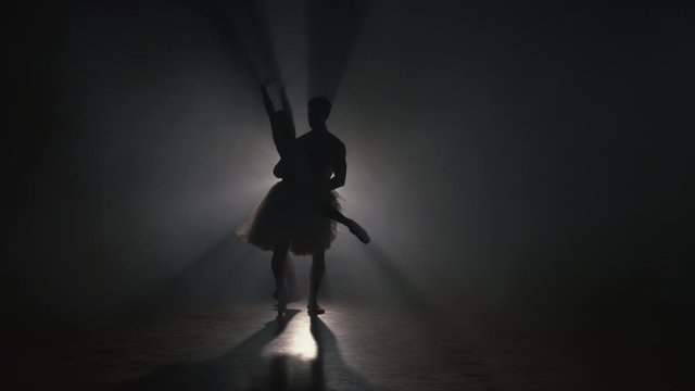 Professional ballet couple dancing in spotlights smoke on big stage. Beautiful young woman and man on floodlights background. Emotional duet performing choreographic art. Slow motion. 4k