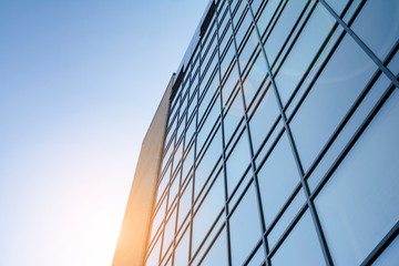 Facade of modern glass building at sunset. Warm and cool tone contrast. Sun flare.