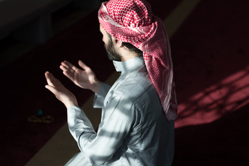 Young Arabic Muslim man  praying. Doing a dailly pray inside modern beautiful mosque.