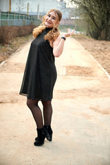 Photo of fashionable blonde girl in a coat on the road outdoors in the spring city