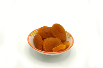 Dried apricots on a ceramic saucer isolated on white background. Energy and fiber natural source. Dieting food.