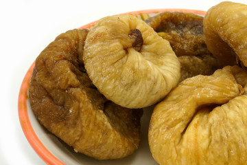 Dried figs on a ceramic saucer isolated on white background. Energy and fiber natural source. Dieting food.