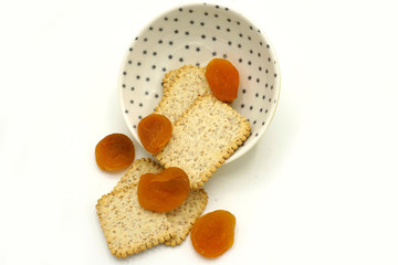 Dried fruits and digestive biscuits on a ceramic saucer isolated on white background. Energy and fiber natural source. Dieting food.