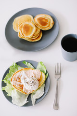 Healthy nutritious tasty breakfast. Pancakes, poached egg on ceramic plate and coffee cup. table setting. food photo. good morning