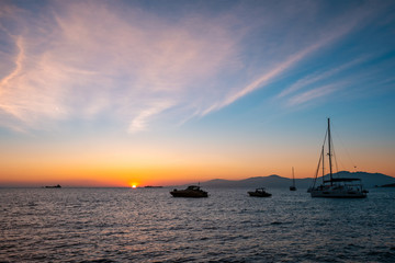 Naklejka na ściany i meble Sunset in Mykonos island, Greece with yachts in the harbor romantic spot on sunset. Mykonos town, Greece