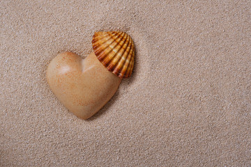 Stone heart with a shell in the sand. 
