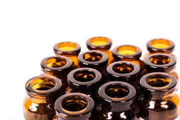 Many empty brown glass medical bottles isolated on a white background. The course of treatment is completed. Mass vaccination. Capacities for tablets. Production of containers.