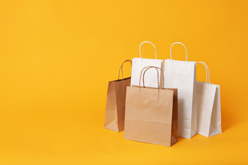 Paper shopping bags on color background
